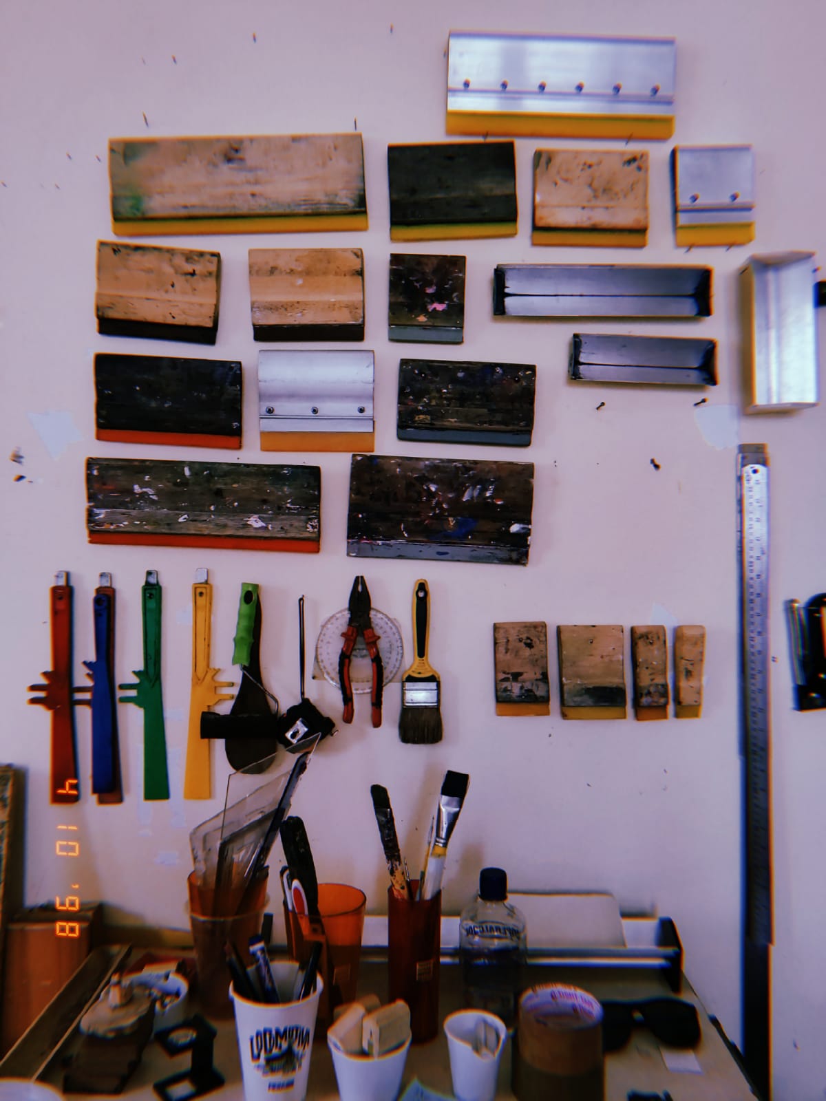 uma foto da parede do ateliê com vários equipamentos de serigrafia pregados